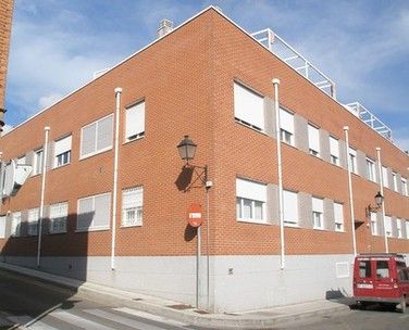 Vista desde la calle de un bloque de viviendas con ventanas metálicas blancas