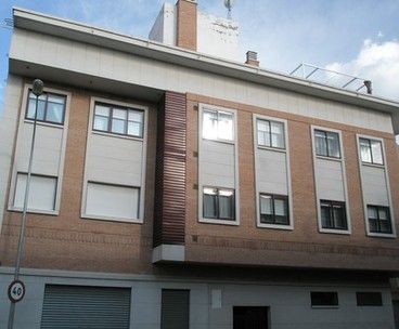 Vista desde la calle de un bloque de viviendas con ventanas metálicas