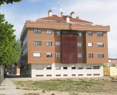 Vista desde la calle de un bloque de viviendas con ventanas metálicas